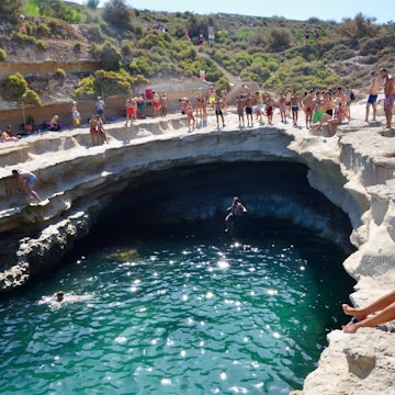 Swimmers and divers at St Peters Pool in Delimara, Malta.