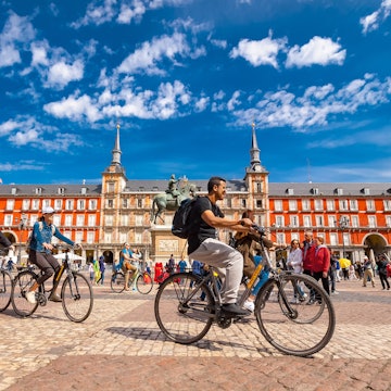 Spain, Madrid..A view of La Plaza Mayor square in Madrid where there were a group of tourists riding bicycles. The Plaza Mayor square is one of the most famous squares in the town and located in the city center. People walk and cycle through the streets.The Plaza Mayor (Main Square) was built during Philip III's reign (1598–1621).